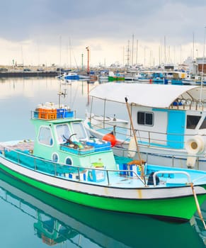 Colorful fishing boats moored in Limassol marina with restaurants on pier, Cyprus