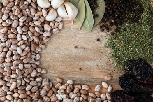 Flat lay of pinto beans, garlic, bay leaves, peppercorns, dried epazote and poblano peppers.