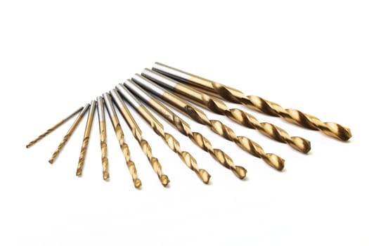 A set of ten drill bits on white with selective focus