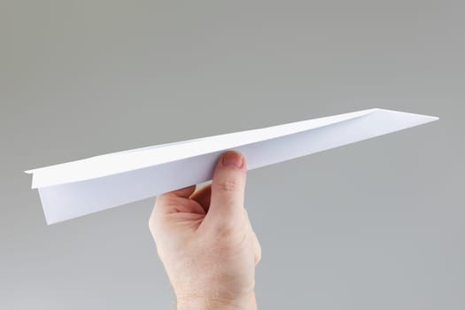 A hand holding a paper dart plane ready to throw