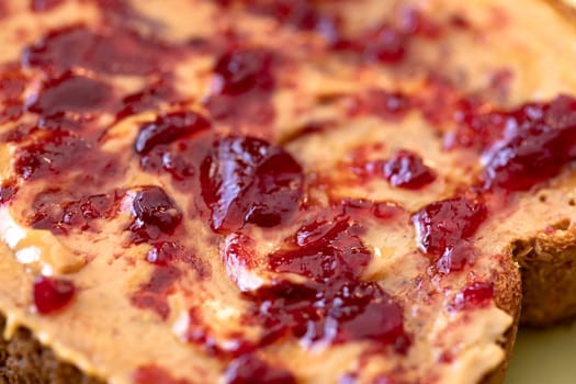 Creamy peanut butter spread with fruit jam on healthy whole wheat toast bread, close-up