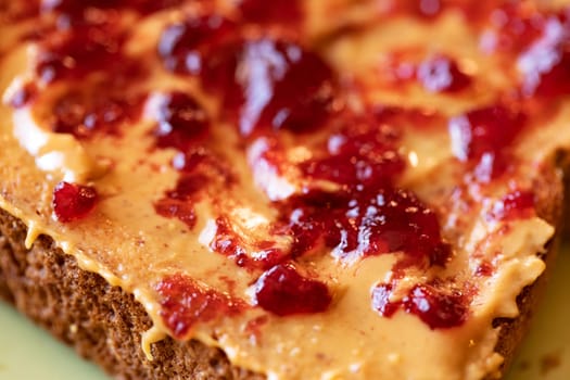 Creamy peanut butter spread with fruit jam on healthy whole wheat toast bread, close-up