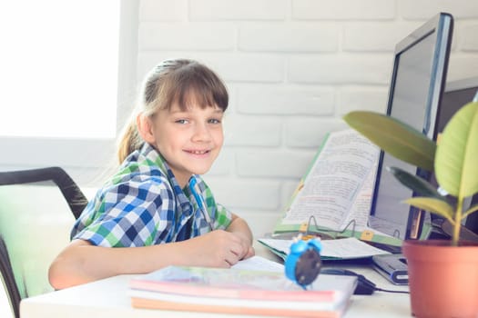 Happy schoolgirl is studying at home and looked into the frame