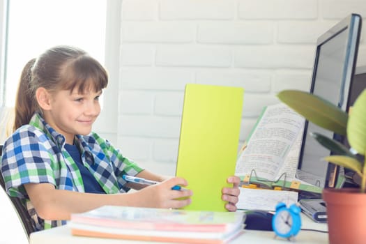 Smiling schoolgirl cheerfully watches a video tutorial on a tablet computer