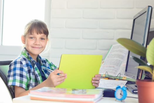 A ten-year-old girl is studying remotely at home and cheerfully looked into the frame.