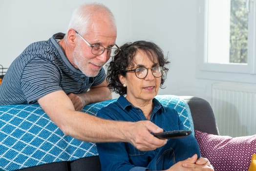 Senior couple relaxing on sofa and watching a tv at home