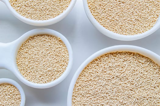 A close up of some measurement baking spoons with yeast on them