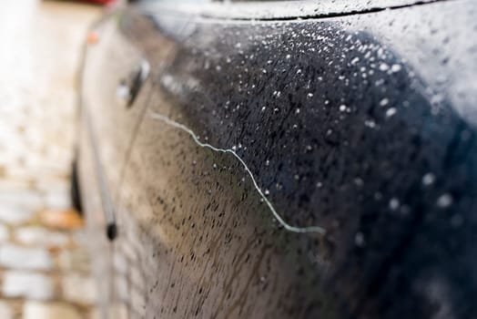 scratched car paint with a handle and tire out of focus