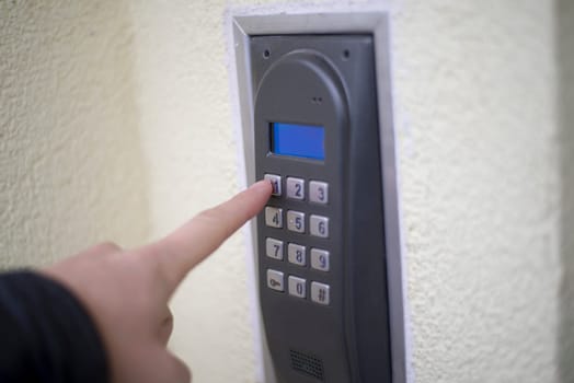 human finger pushing button of house intercom