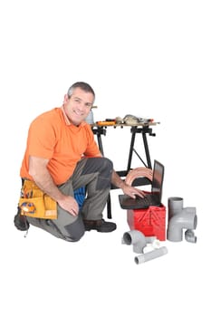 Labourer kneeling by laptop computer
