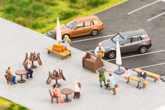Social distancing of miniature people at a sidewalk cafe