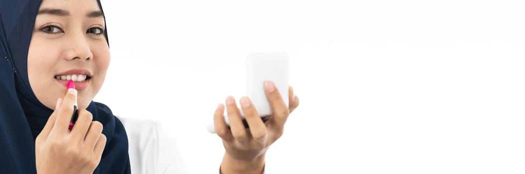 Young Muslim woman hold cosmetic and looking to camera to review product as vlog and blogger on white background taken in studio. Using for Fashion and beauty concept