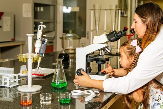 All hands on board, female doctor and little helper checking covid 19 virus samples under microscope to help with discovery of coronavirus vaccination