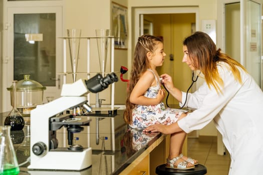 Caucasian white, female doctor checking chest, lungs and hart of young girl with a stethoscope in a hospital laboratory, no coronavirus detected