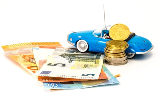 Stacks of giant silver coins and banknotes next to a new blue hoodable car