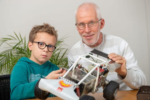 grandpa and son little boy repairing  model radio-controlled car at home