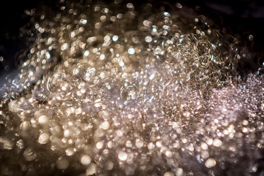 Soap bubbles in a foam carpet with blurred dark areas in the foreground and background