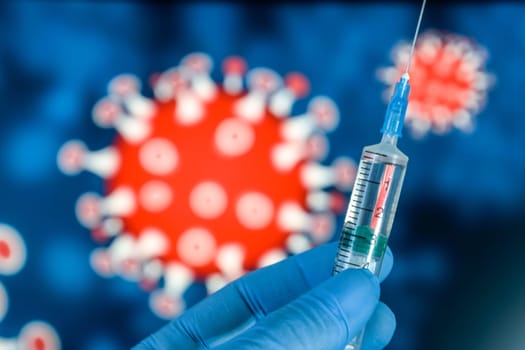 Coronavirus vaccine. A hand in medical gloves holds a vaccine and a syringe against the background of the image of a coronavirus. covid-19