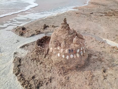 Sand castle on the beach with shells. Children's games at sea.