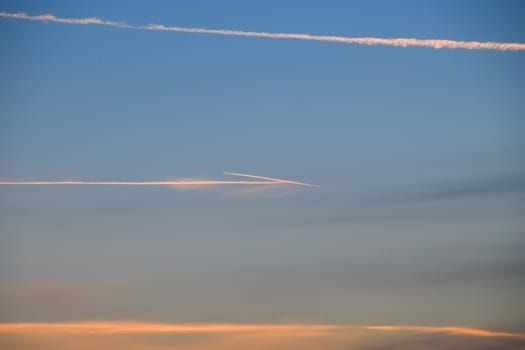 Contrail from an airplane on a blue sky against a sunset.
