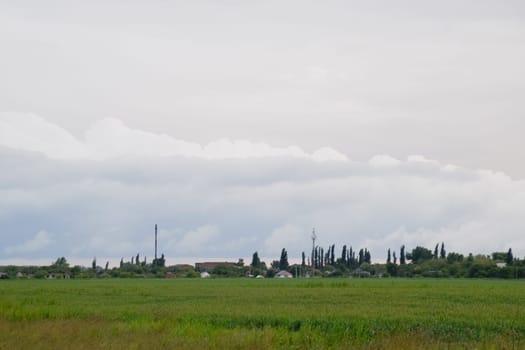 Cloudy landscape, the village before the rain, visible large cumulus clouds and clouds over the village.