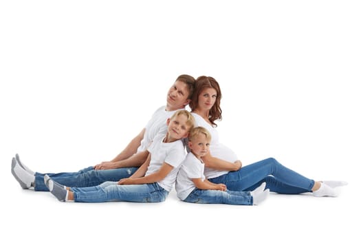 Friendly family. Young pregnant woman and her husband are sitting with backs to each other with children, Isolated on a white background.  Happy parents. Pregnant mother and father with two sons