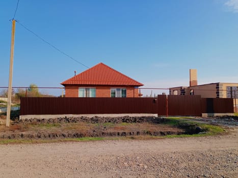 A new house with an orange roof and a brown fence.