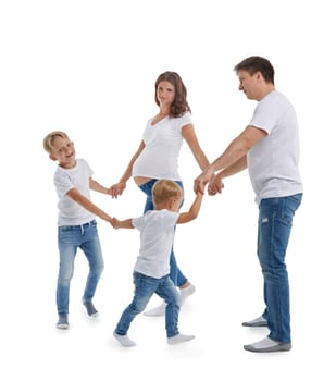 Pregnant mother and father with two sons on white background. Parents with children are playing: holding hands in circles and walking or dancing around. Happy friendly family. Concept of parenting