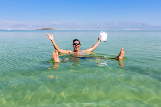 Man with open arms. Dead Sea coastline. Salt crystals at sunset. Texture of Dead sea. Salty sea shore