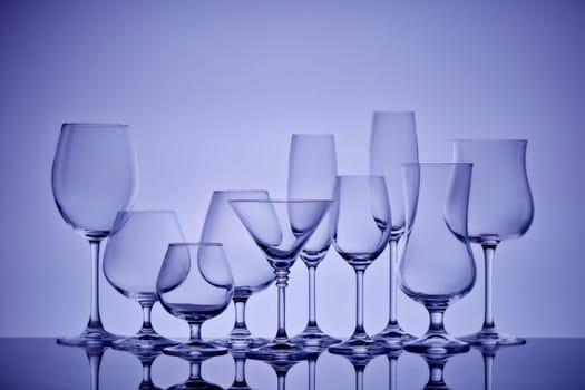 Set of glasses for different alcoholic drinks and cocktails on light gray background. Empty clear glassware.