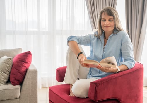 Mature woman reading a book in her urban apartment