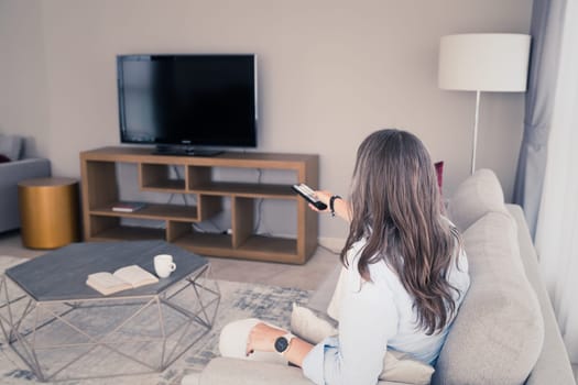 A woman on a sofa getting ready to watch TV