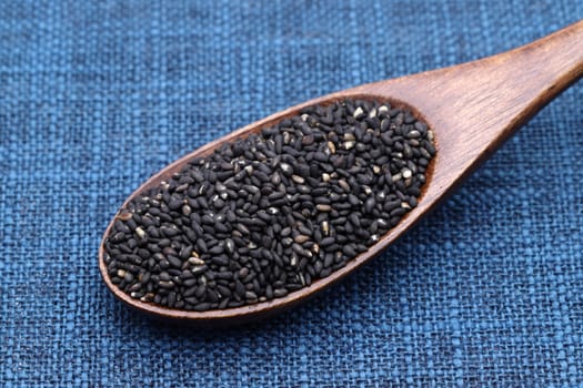 black sesame seeds in a wooden spoon on table