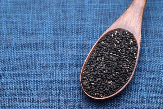 black sesame seeds in a wooden spoon on table