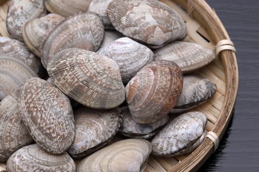 Japanese asari clams in a bamboo basket on wooden table