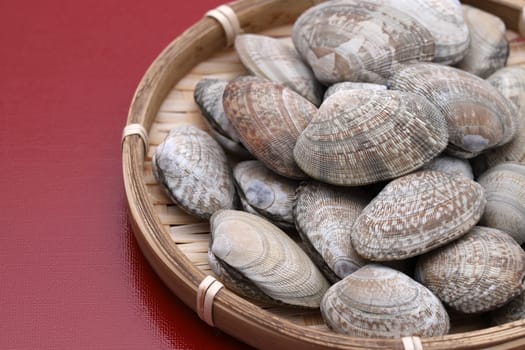 Japanese asari clams in a bamboo basket on wooden table