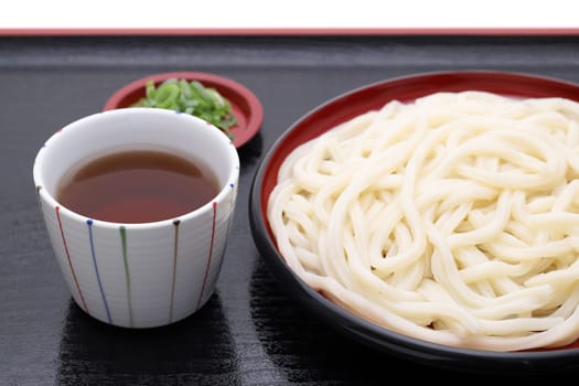 Japanese Zaru udon noodles in a plate with soy sauce on white background