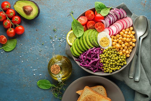 Healthy vegan lunch bowl. Vegetable salad with Avocado, chickpeas, tomato, red cabbage, green peas, red onion and egg