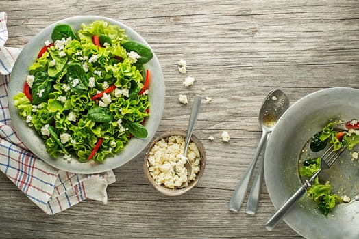 Healthy green salad with fresh cheese on wooden table background. Healthy salad meal.