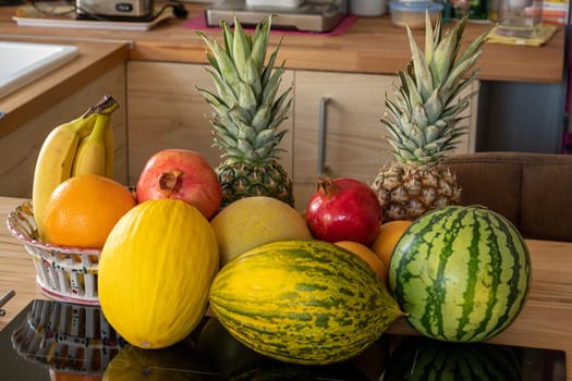 Many varieties of fresh and exotic fruits standing on a cooking island in a domestic kitchen