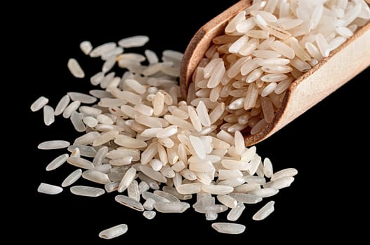 White rice in wooden scoop closeup on black background