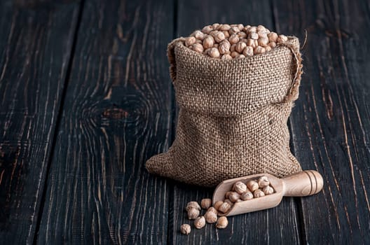 Chickpea in sack and scoop near on wooden table