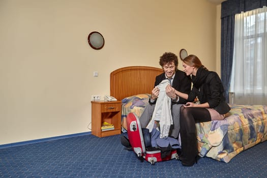 Happy young family with suitcases sits in the bed. Vacation.