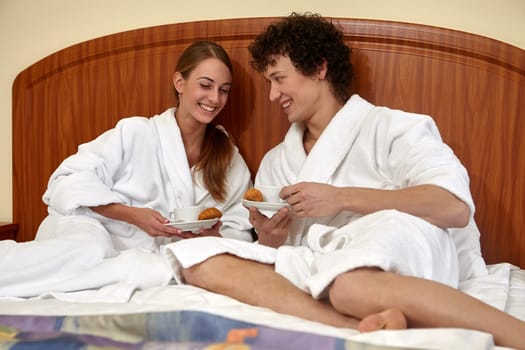 Happy young family  with breakfast lies in the bed at home.