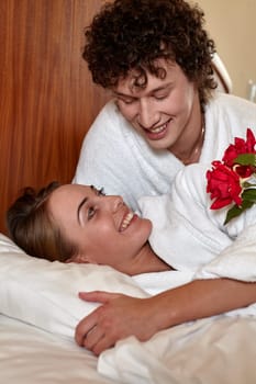 Happy young family with roses lies in the bed at home. Valentine's Day