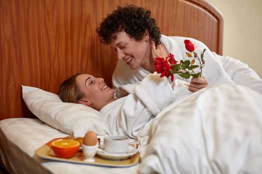 Happy young family  with breakfast lies in the bed at home.