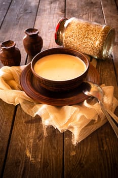 Boiled buckwheat with milk in wooden bowl on rustic wooden table, vertical