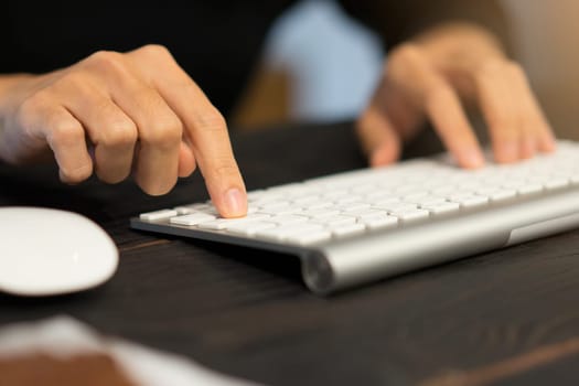 Hands typing on wireless keyboard for computer in an office.