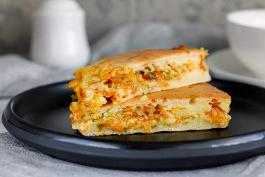 Pieces of pie with fresh young cabbage and carrots on a ceramic dish, hearty breakfast