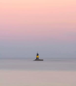 Lighthouse of Burela, Spain surrounded by the sea with silky effect and sky in pastel tones